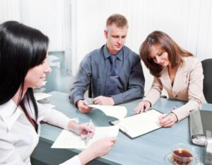 AA Rental Property couple-signing-papers-in-office-with-black-haired-female-agent